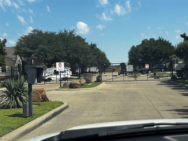 827 Kitty Hawk Ln, Grand Prairie, TX 75051 - view of concrete street with curbs, a gate, a gated entry, and traffic signs