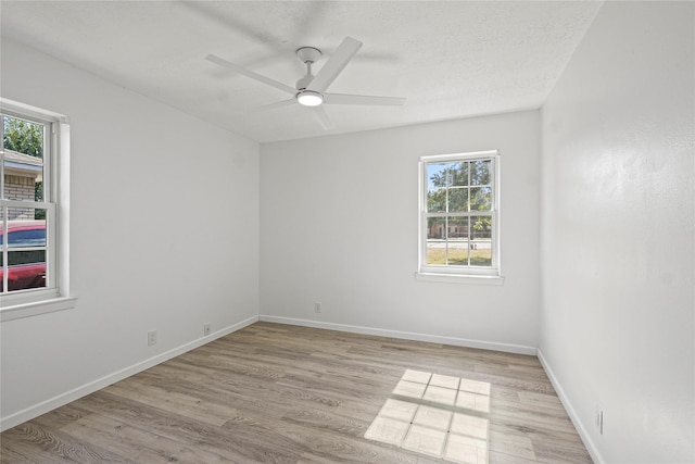 empty room featuring light wood-type flooring, healthy amount of natural light, and ceiling fan
