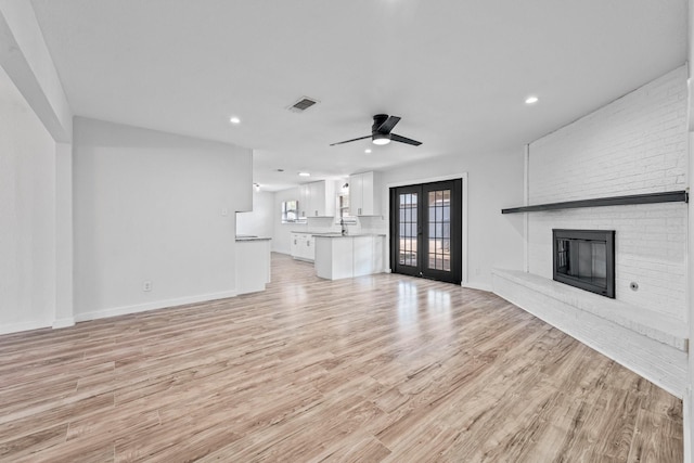 600 Circleview Dr N, Hurst, TX 76054 - unfurnished living room with french doors, recessed lighting, light wood-style floors, a brick fireplace, and baseboards