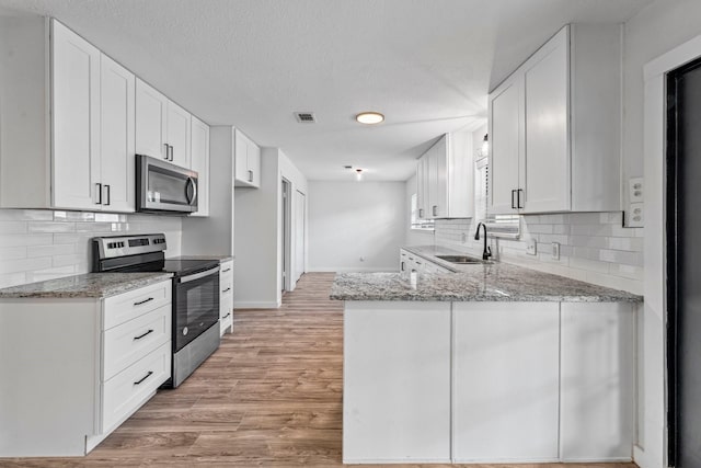 600 Circleview Dr N, Hurst, TX 76054 - kitchen featuring appliances with stainless steel finishes, a sink, a peninsula, light stone countertops, and baseboards