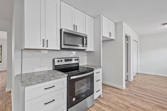 600 Circleview Dr N, Hurst, TX 76054 - kitchen with stainless steel appliances, baseboards, decorative backsplash, white cabinets, and light wood-style flooring