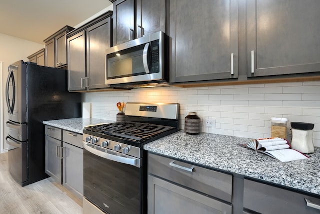 2825 Hale Rd, Celina, TX 75009 - kitchen with stainless steel appliances, light wood-style floors, light stone counters, backsplash, and gray cabinets