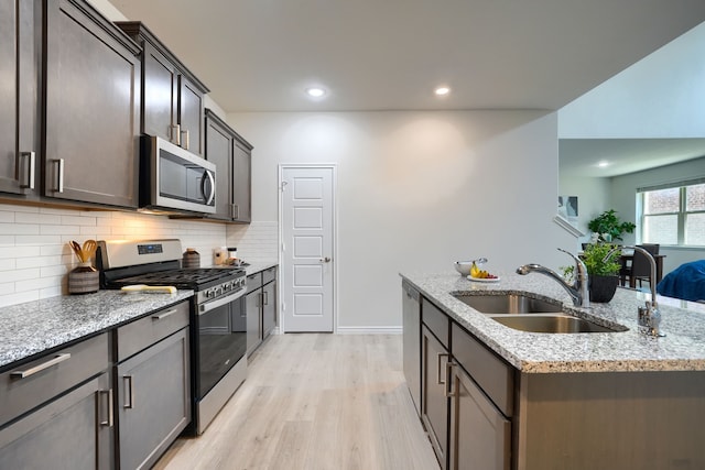 2825 Hale Rd, Celina, TX 75009 - kitchen with stainless steel appliances, a sink, light wood-style flooring, light stone counters, and tasteful backsplash