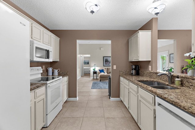 kitchen featuring white appliances, a sink, a textured ceiling, light tile patterned floors, and stone countertops