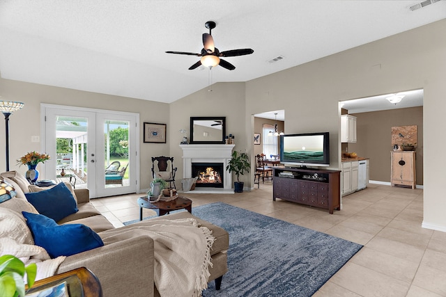 living area featuring a ceiling fan, light tile patterned floors, vaulted ceiling, baseboards, and french doors