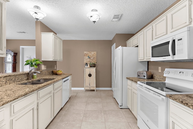 kitchen featuring white appliances, a sink, baseboards, a textured ceiling, and white cabinets