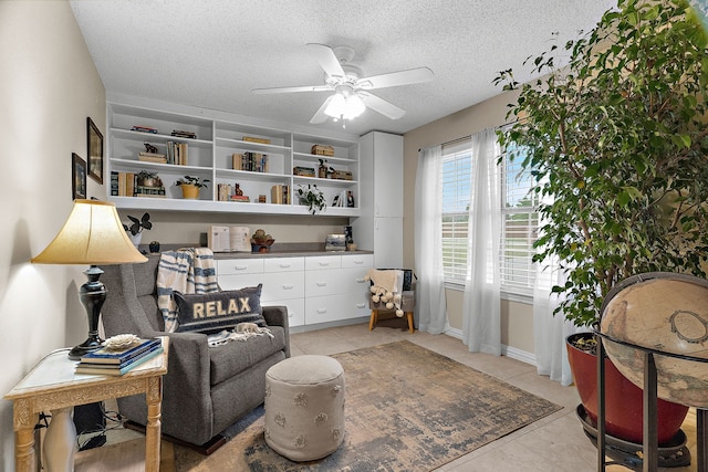 sitting room with a ceiling fan, a textured ceiling, and light tile patterned floors