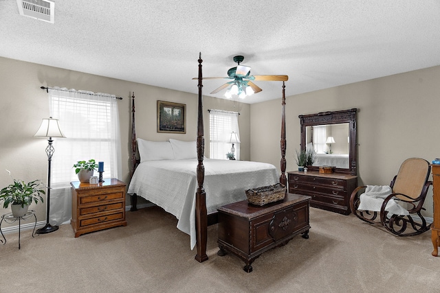 bedroom featuring light colored carpet, a textured ceiling, ceiling fan, and baseboards