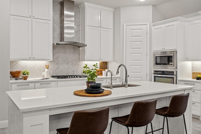 1429 Bridgewater Blvd, Celina, TX 75009 - kitchen with wall chimney range hood, stainless steel appliances, a sink, an island with sink, and white cabinets