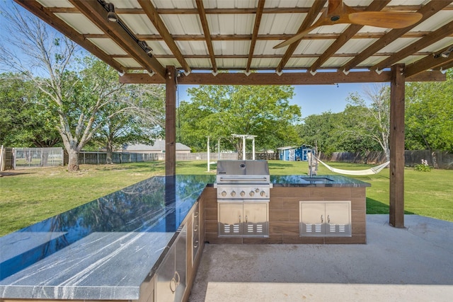 view of patio / terrace with area for grilling, an outdoor kitchen, a sink, an outdoor structure, and a storage shed