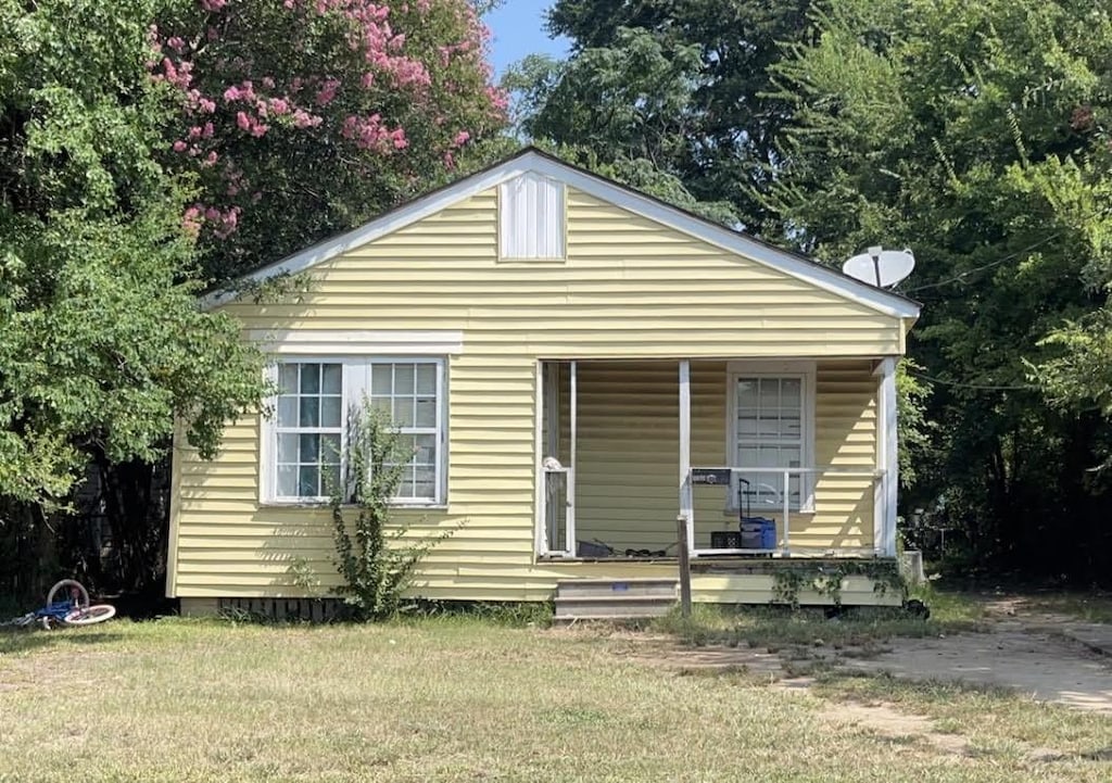 view of front of home with covered porch and a front lawn
