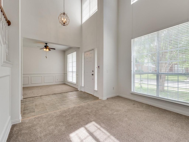carpeted entryway with a chandelier, a high ceiling, ceiling fan, and tile patterned floors