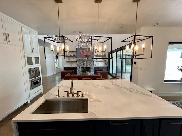 613 Wildcat Way, Kennedale, TX 76060 - kitchen with a sink, a fireplace, a kitchen island with sink, oven, and baseboards