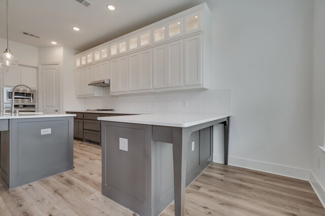 14936 Grissom Ave, Aledo, TX 76008 - kitchen featuring light wood-type flooring, under cabinet range hood, a peninsula, decorative backsplash, and recessed lighting