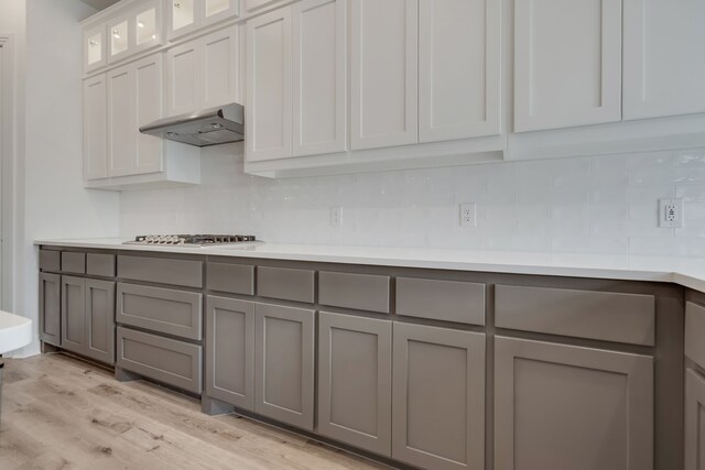 14936 Grissom Ave, Aledo, TX 76008 - kitchen featuring gray cabinetry, stainless steel gas cooktop, decorative backsplash, under cabinet range hood, and light wood-style flooring