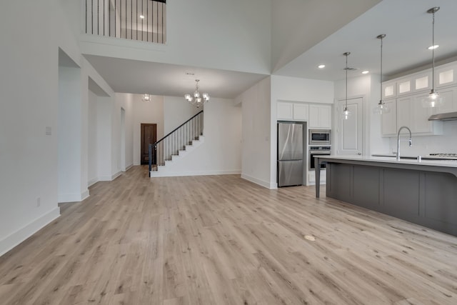 14936 Grissom Ave, Aledo, TX 76008 - kitchen with appliances with stainless steel finishes, light wood-style flooring, a high ceiling, white cabinetry, and baseboards