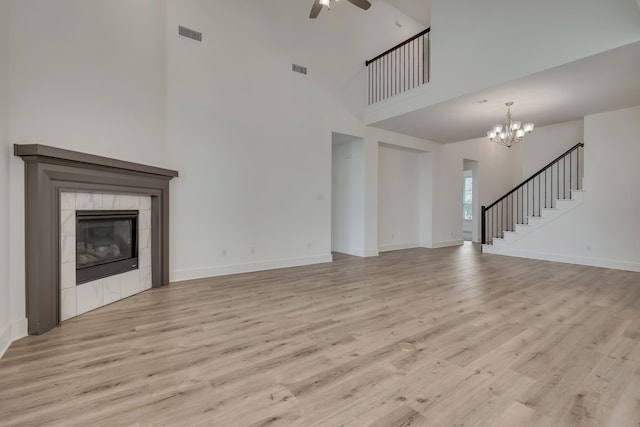 14936 Grissom Ave, Aledo, TX 76008 - unfurnished living room with a ceiling fan, light wood-style floors, baseboards, a high ceiling, and a tile fireplace