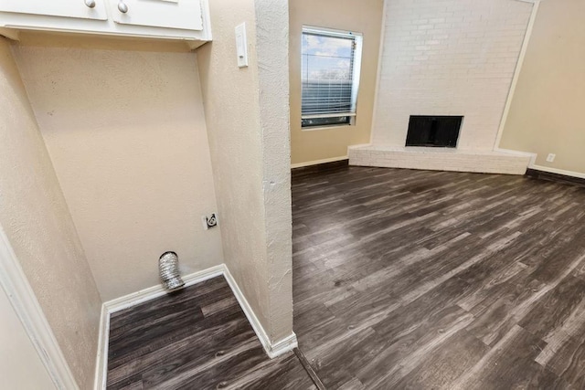 laundry area with dark wood-style floors, baseboards, and a fireplace