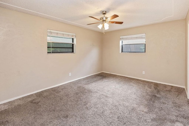 unfurnished room with plenty of natural light, carpet floors, a ceiling fan, baseboards, and a textured ceiling