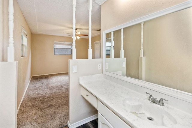 bathroom featuring ceiling fan, a textured ceiling, vanity, and baseboards