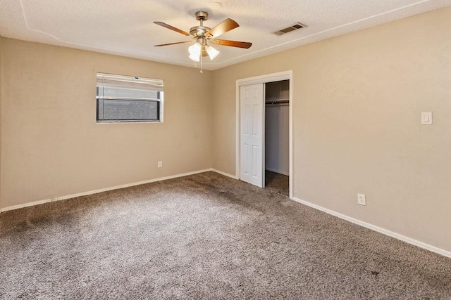 unfurnished bedroom featuring carpet, a closet, baseboards, a ceiling fan, and a textured ceiling