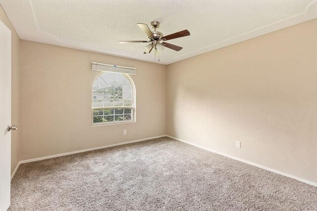 carpeted empty room with ceiling fan, baseboards, and a textured ceiling