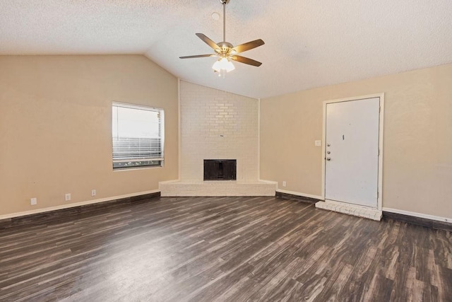 unfurnished living room with ceiling fan, dark wood-style flooring, vaulted ceiling, a brick fireplace, and baseboards