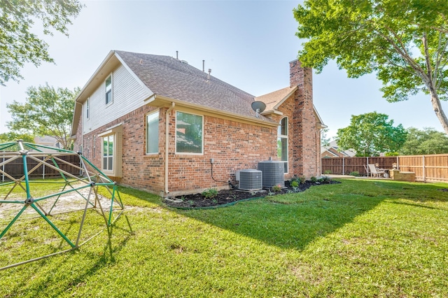 2401 Greenwich Dr, Carrollton, TX 75006 - back of property with brick siding, a chimney, roof with shingles, and central AC unit