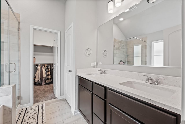 10116 Mickler Ln, Waco, TX 76708 - bathroom featuring a stall shower, lofted ceiling, a spacious closet, double vanity, and baseboards