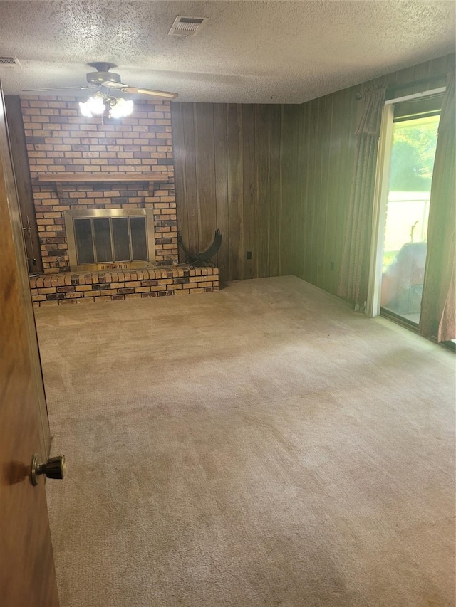 6313 Westwood Rd, Shreveport, LA 71129 - unfurnished living room featuring carpet, a textured ceiling, a fireplace, ceiling fan, and wooden walls