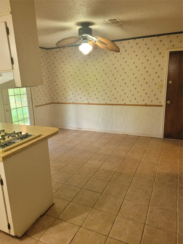 6313 Westwood Rd, Shreveport, LA 71129 - spare room featuring ceiling fan, a textured ceiling, wallpapered walls, and light tile patterned floors