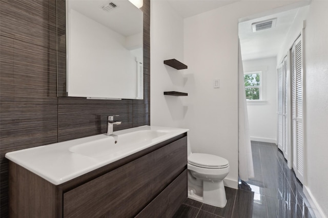 10834 Wyatt St, Dallas, TX 75218 - bathroom featuring toilet, vanity, baseboards, and decorative backsplash