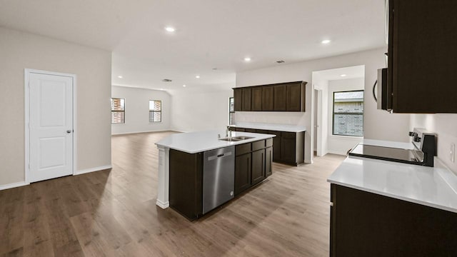 440 Drake Dr, Ferris, TX 75125 - kitchen featuring stainless steel appliances, light wood-style flooring, dark brown cabinetry, an island with sink, and light countertops