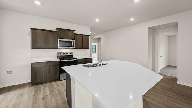 440 Drake Dr, Ferris, TX 75125 - kitchen featuring stainless steel appliances, light wood finished floors, an island with sink, light countertops, and recessed lighting