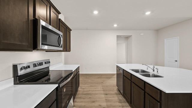 440 Drake Dr, Ferris, TX 75125 - kitchen featuring stainless steel appliances, light wood-type flooring, recessed lighting, dark brown cabinetry, and a kitchen island with sink