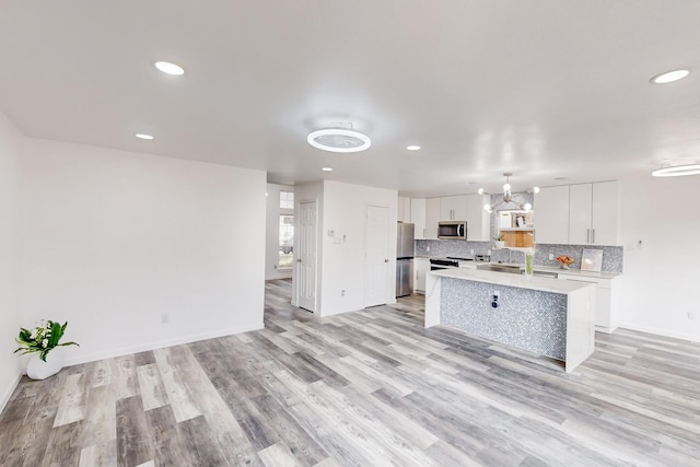 827 Astaire Ave, Duncanville, TX 75137 - kitchen with stainless steel microwave, a center island, white cabinetry, light countertops, and light wood-type flooring