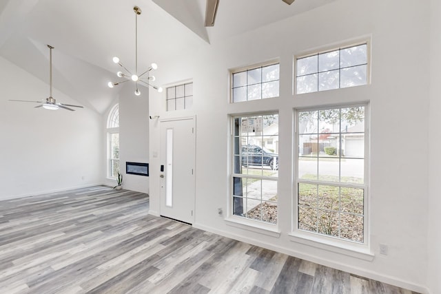 827 Astaire Ave, Duncanville, TX 75137 - unfurnished living room featuring ceiling fan, high vaulted ceiling, light wood-type flooring, a chandelier, and baseboards