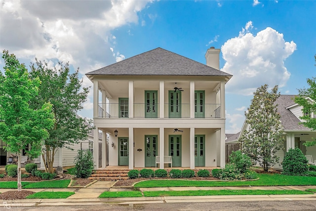 view of front of property featuring ceiling fan, a balcony, a shingled roof, a porch, and stucco siding