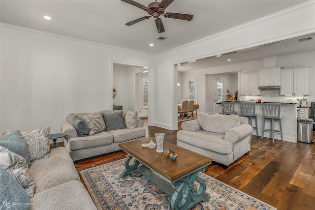 living room featuring ceiling fan, ornamental molding, dark wood-type flooring, and recessed lighting
