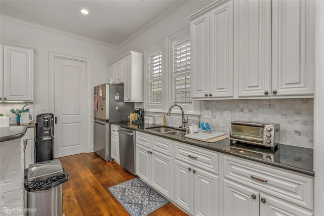 kitchen featuring appliances with stainless steel finishes, a sink, white cabinets, tasteful backsplash, and dark wood finished floors