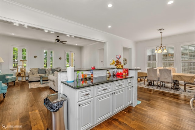 kitchen featuring dark wood finished floors, white cabinetry, dark countertops, crown molding, and a chandelier
