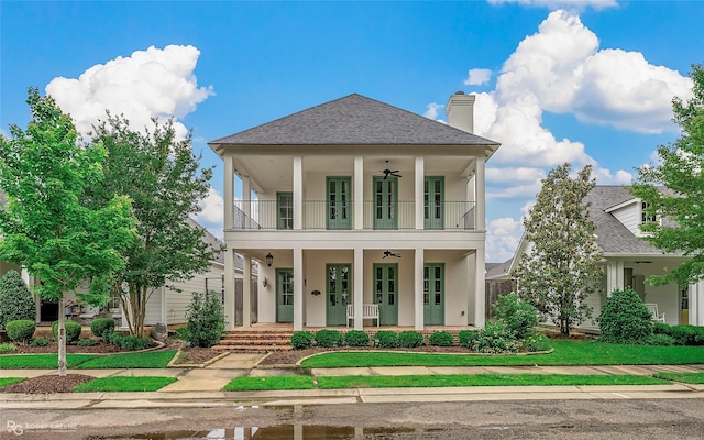 rear view of property with a balcony, ceiling fan, a porch, a chimney, and a shingled roof