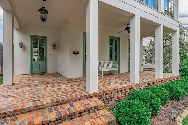 entrance to property with covered porch, stucco siding, and ceiling fan