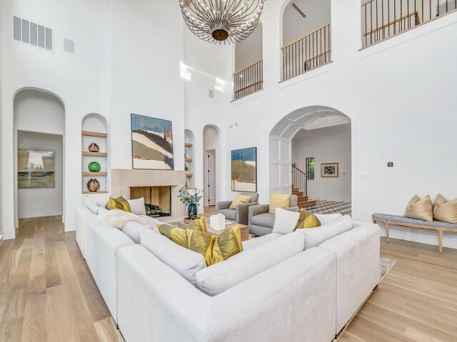 4633 Willow Ln, Dallas, TX 75244 - living area featuring built in shelves, a high ceiling, light wood-type flooring, arched walkways, and stairs