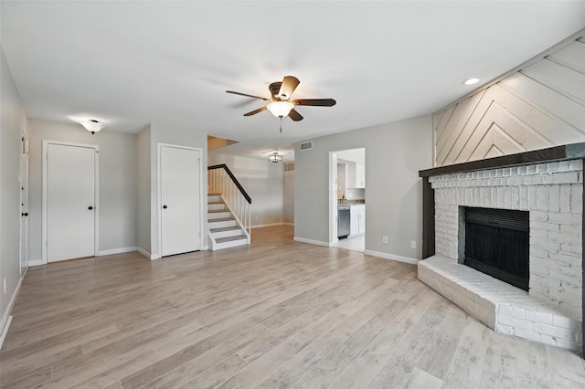 14800 Enterprise Dr Unit 17A, Farmers Branch, TX 75234 - unfurnished living room featuring stairway, ceiling fan, a fireplace, light wood-type flooring, and baseboards