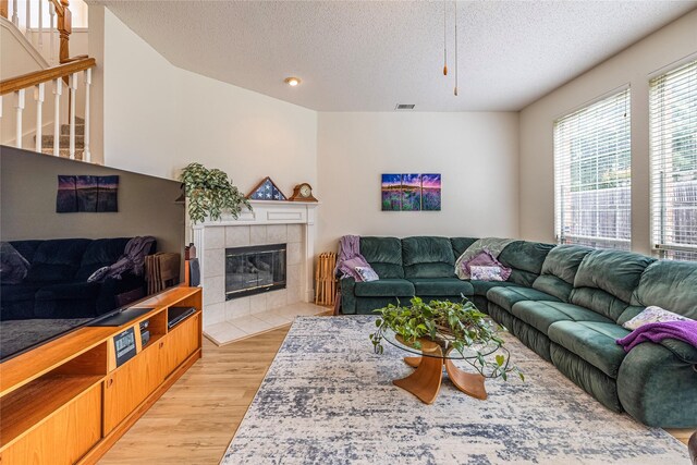 5929 Meadowcrest Ln, Sachse, TX 75048 - living room with light wood-type flooring, a textured ceiling, and a tile fireplace