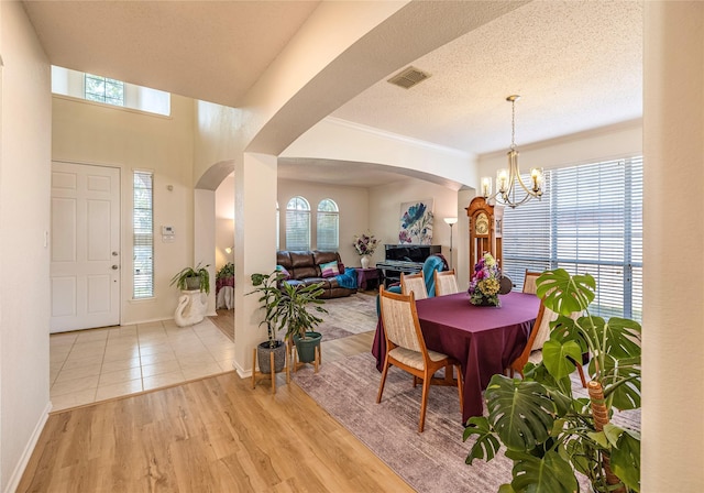 5929 Meadowcrest Ln, Sachse, TX 75048 - dining area featuring arched walkways, a chandelier, light wood finished floors, crown molding, and baseboards