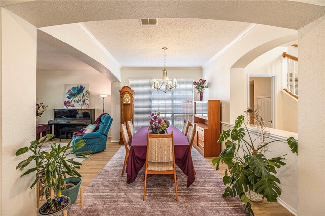 5929 Meadowcrest Ln, Sachse, TX 75048 - dining room with crown molding, arched walkways, light wood-type flooring, a chandelier, and a textured ceiling