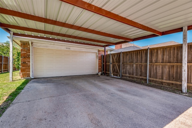 garage featuring fence and a carport