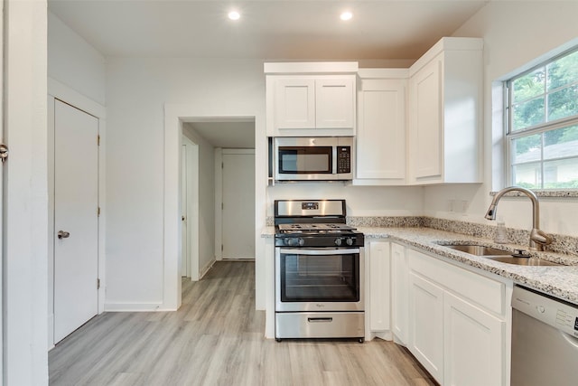 4423 Colonial Ave, Dallas, TX 75215 - kitchen with stainless steel appliances, a sink, light wood-style flooring, white cabinets, and recessed lighting